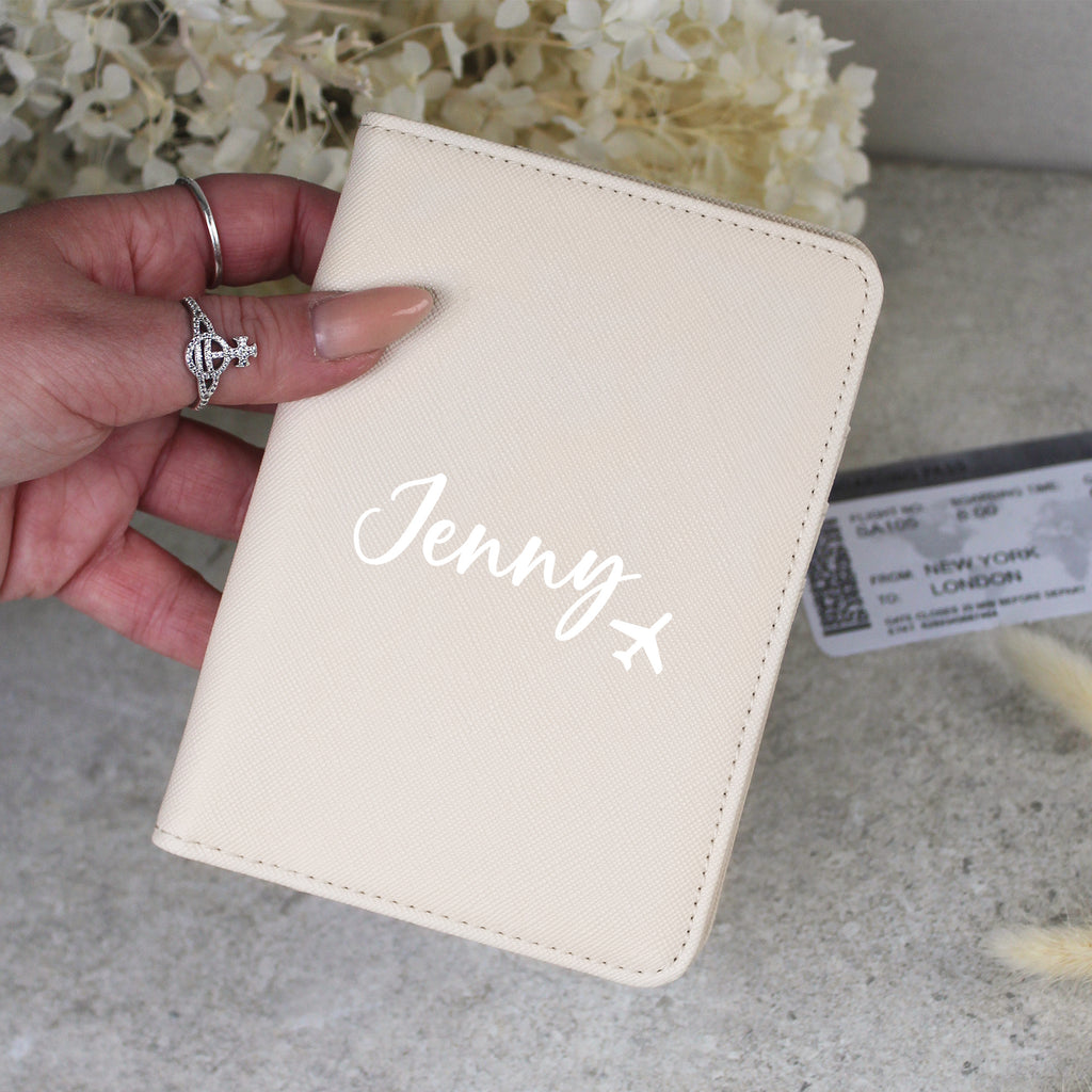 Beige passport holder with 'Jenny' engraved, held by a hand.