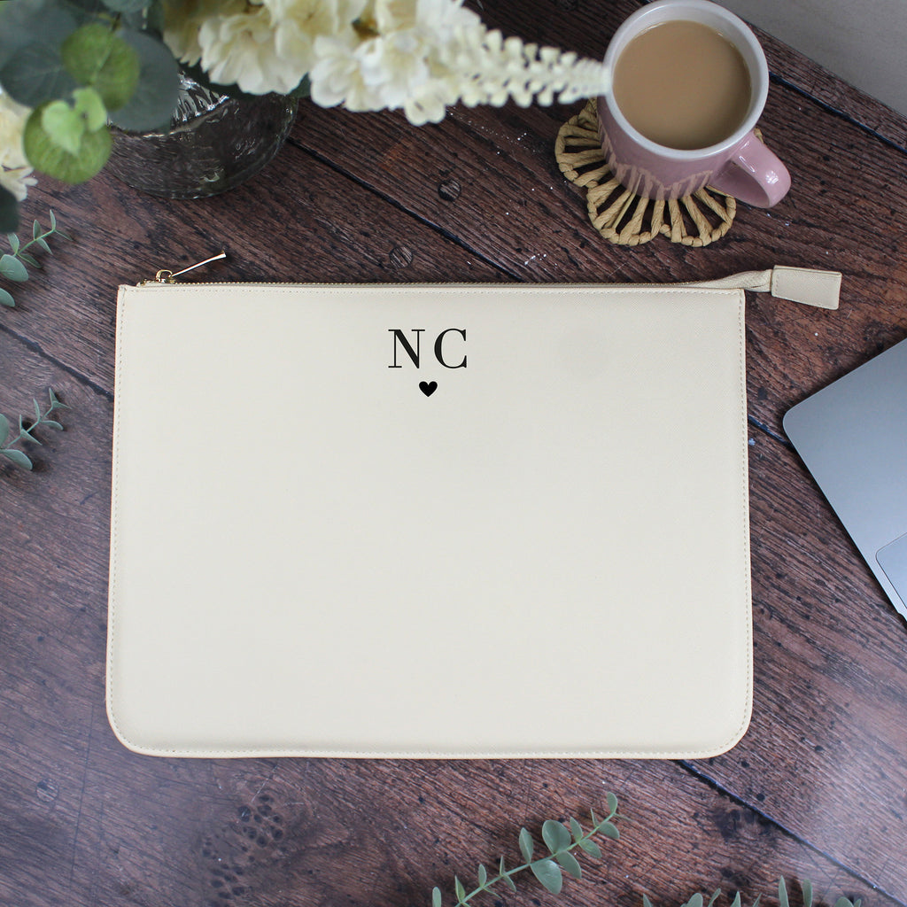 Beige pouch with 'NC' initials on a wooden surface with a cup of coffee and flowers.