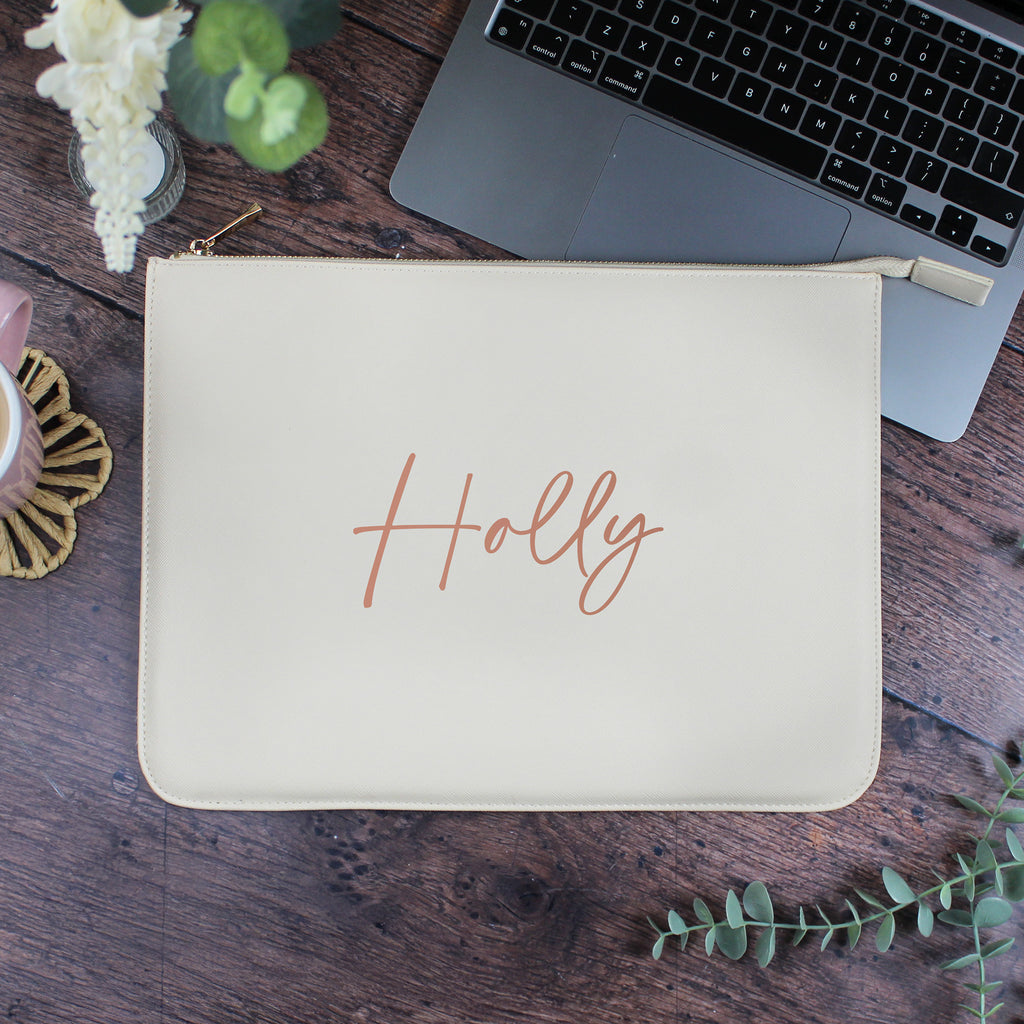 Beige pouch with 'Holly' branding on a wooden surface with a laptop and decorative elements.
