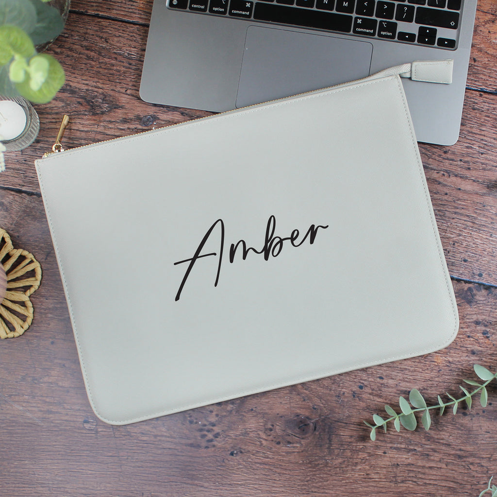 Laptop with a beige pouch labeled 'Amber' on a wooden surface.