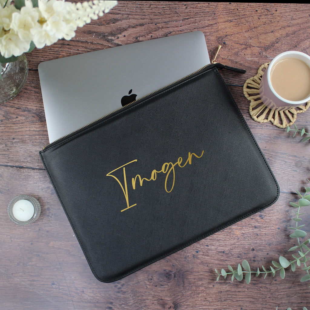 Black laptop sleeve with 'Imogen' branding on a wooden surface with a laptop and coffee cup.