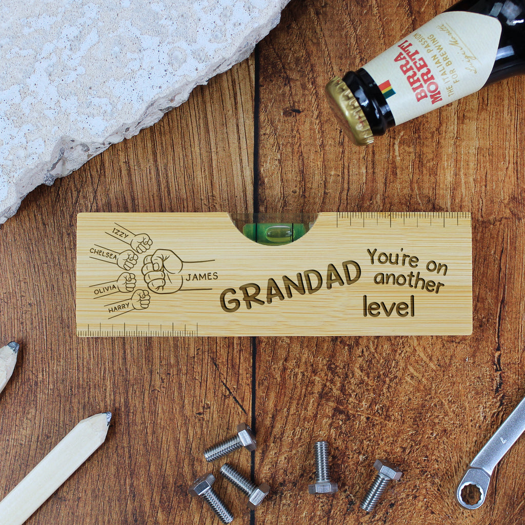 Wooden level with engraved text on a wooden surface with tools and a bottle.