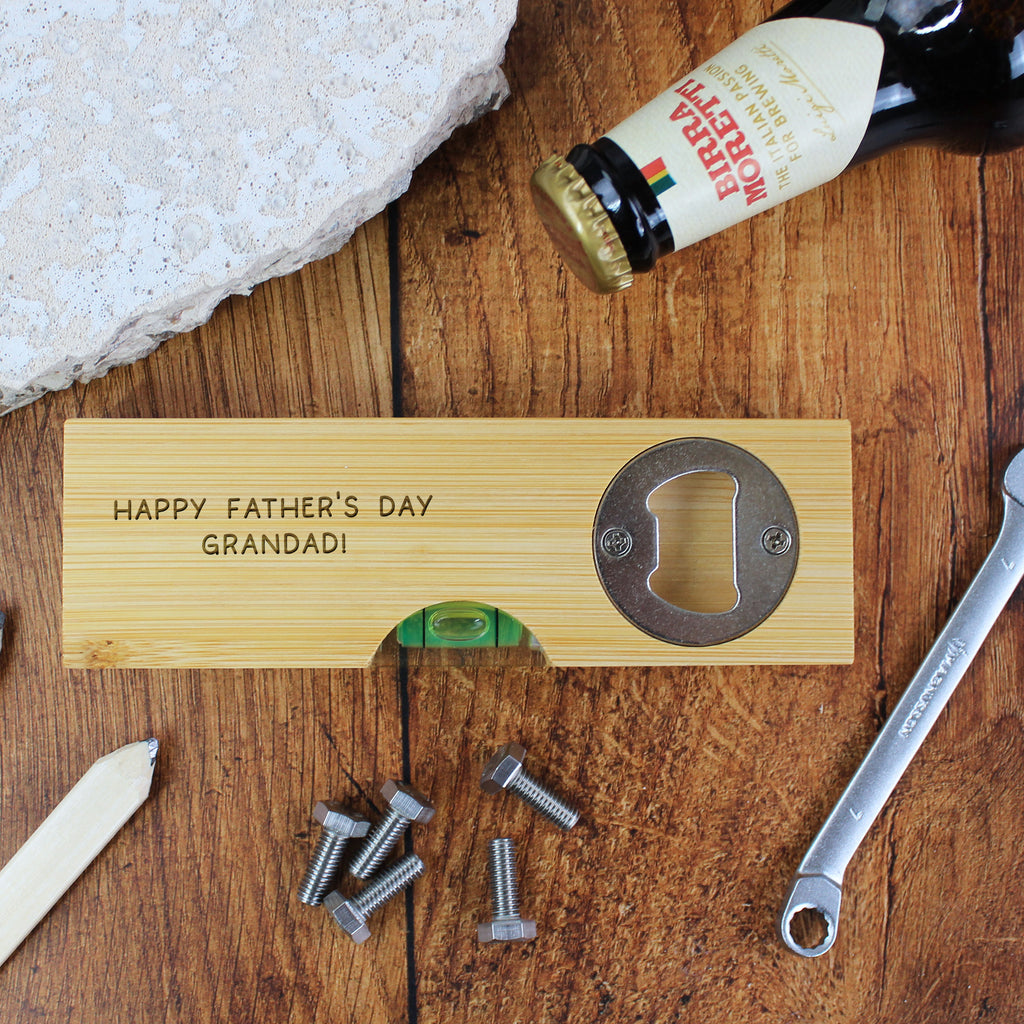 Wooden bottle opener with 'Happy Father's Day Grandad!' engraving on a wooden surface with tools and a beer bottle.