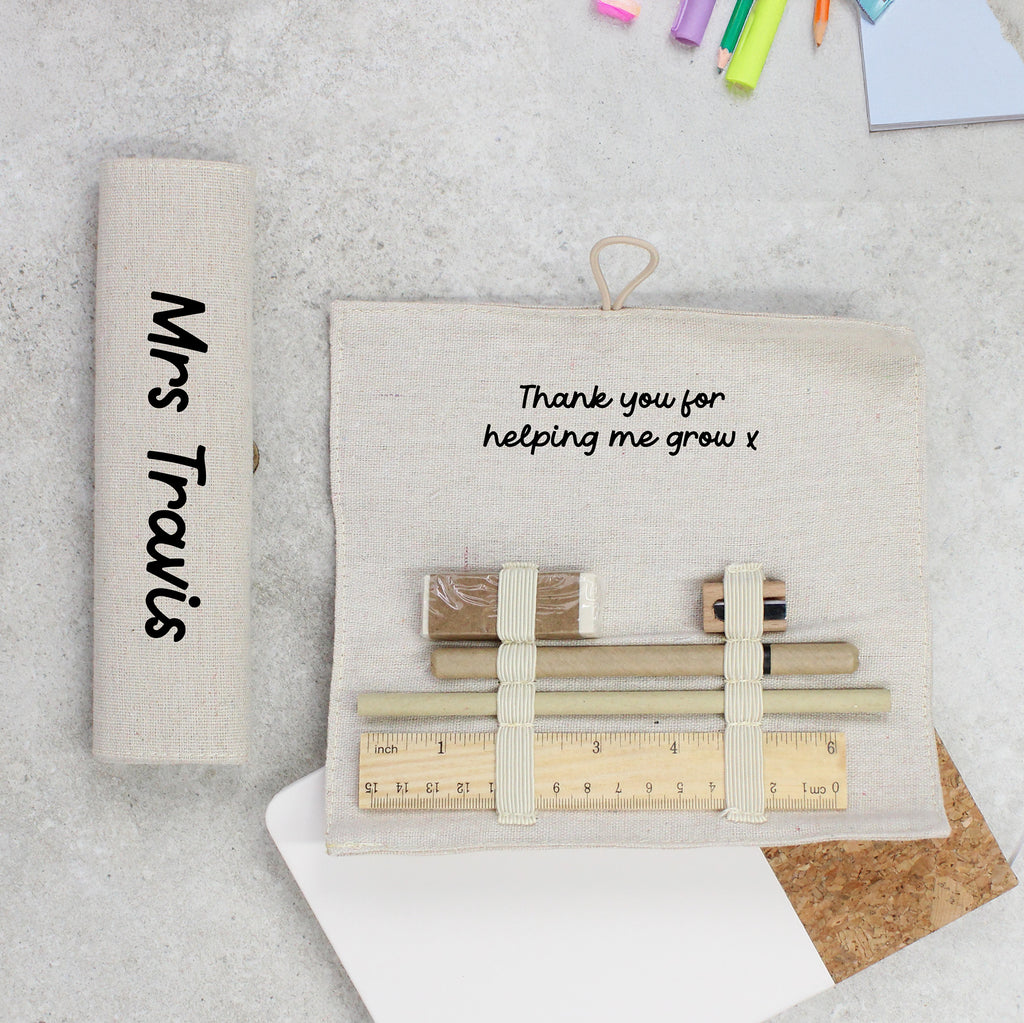 Personalized pouch with stationery items and engraved message on a textured surface.