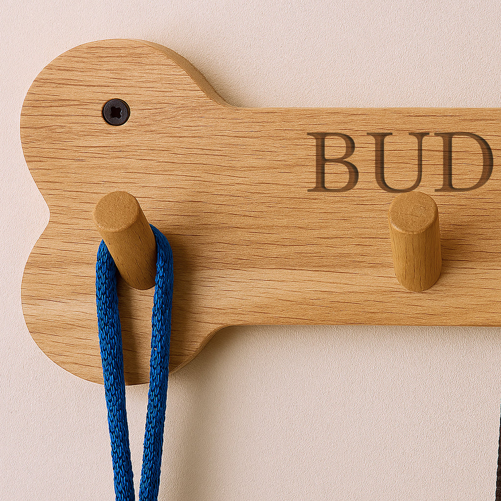 Wooden dog-shaped hook with 'BUD' engraving on a beige wall.