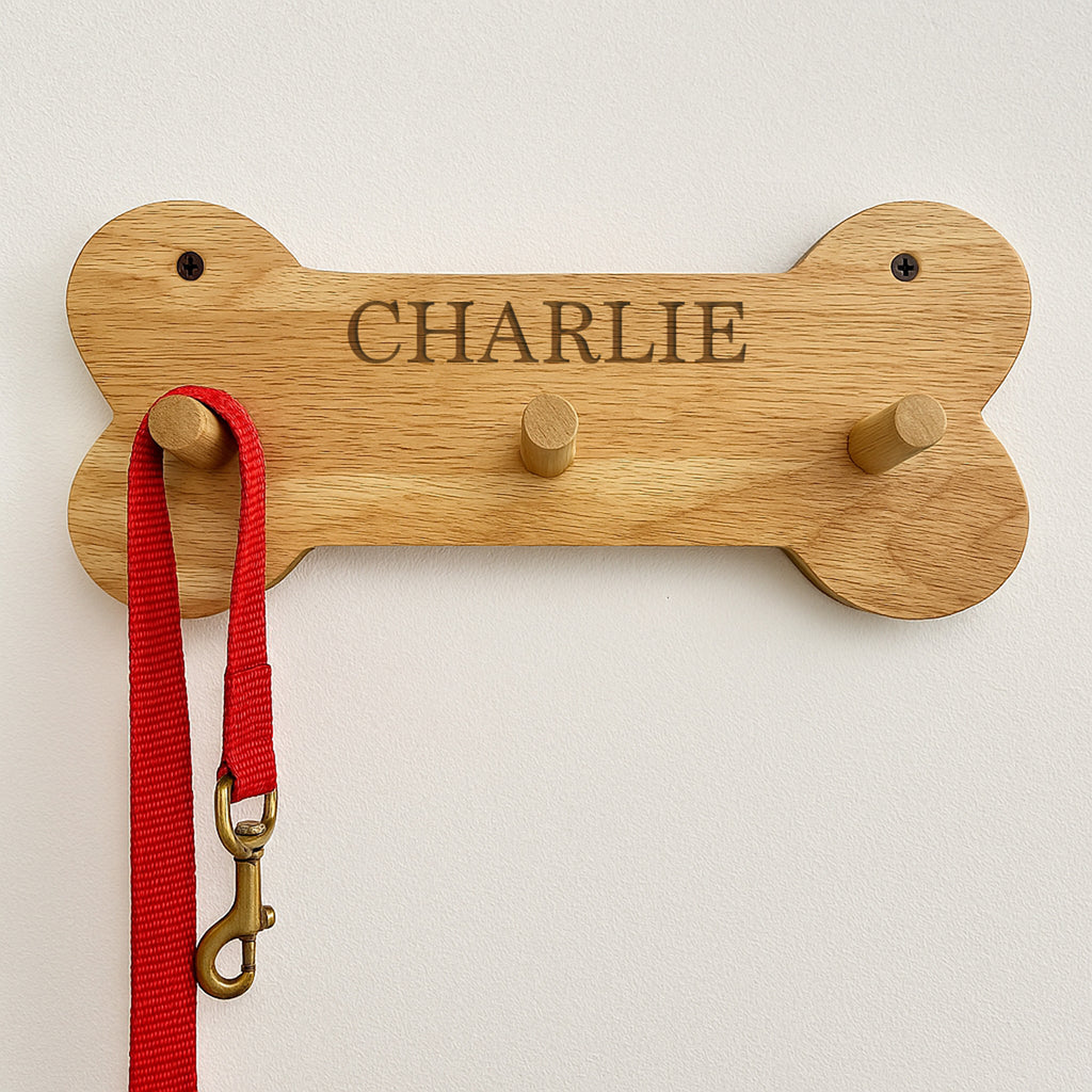 Wooden bone-shaped hook with 'CHARLIE' engraving, holding a red leash.