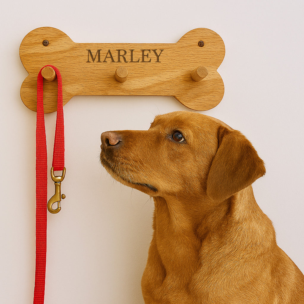 Dog with a red leash attached to a wooden bone-shaped leash holder with 'MARLEY' engraved on it.