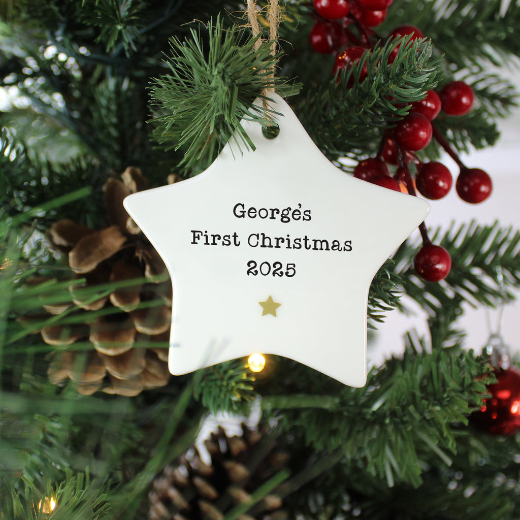 Star-shaped ornament with 'Georges First Christmas 2025' text on a Christmas tree.