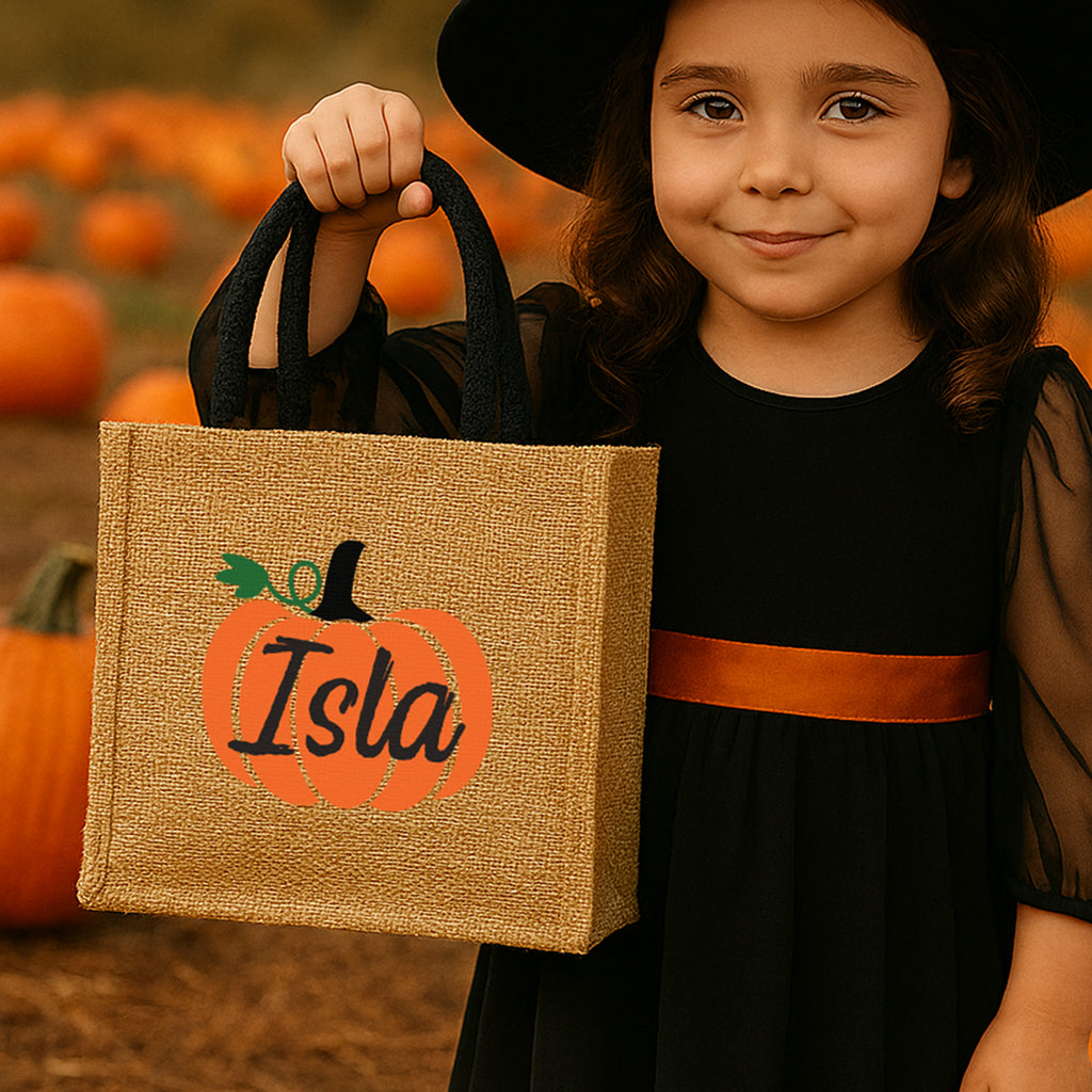 Child in Halloween costume holding a personalized bag with pumpkins in the background