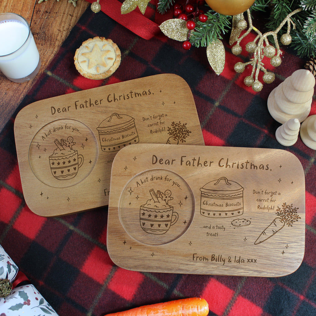 Two wooden platters with engraved Christmas messages on a festive tablecloth.