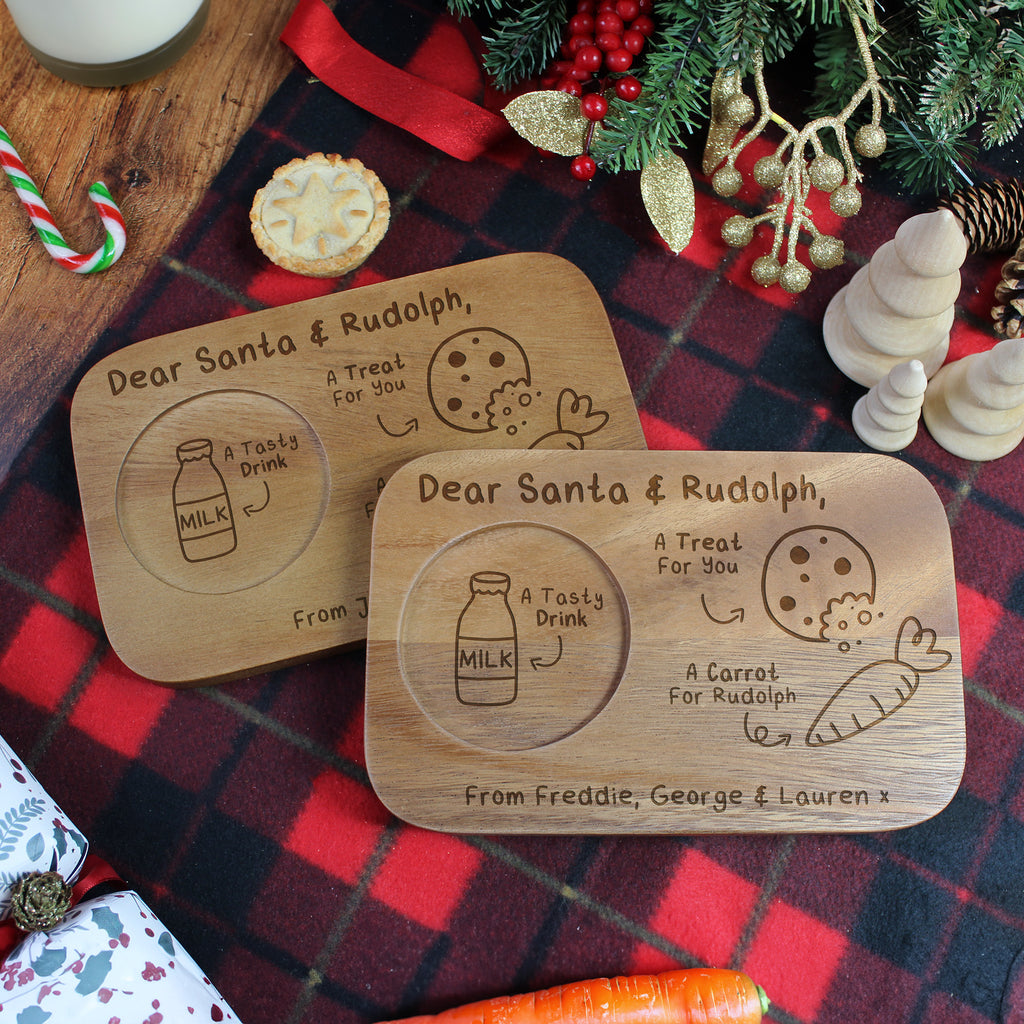Two wooden Christmas coasters with engraved designs on a plaid fabric background.