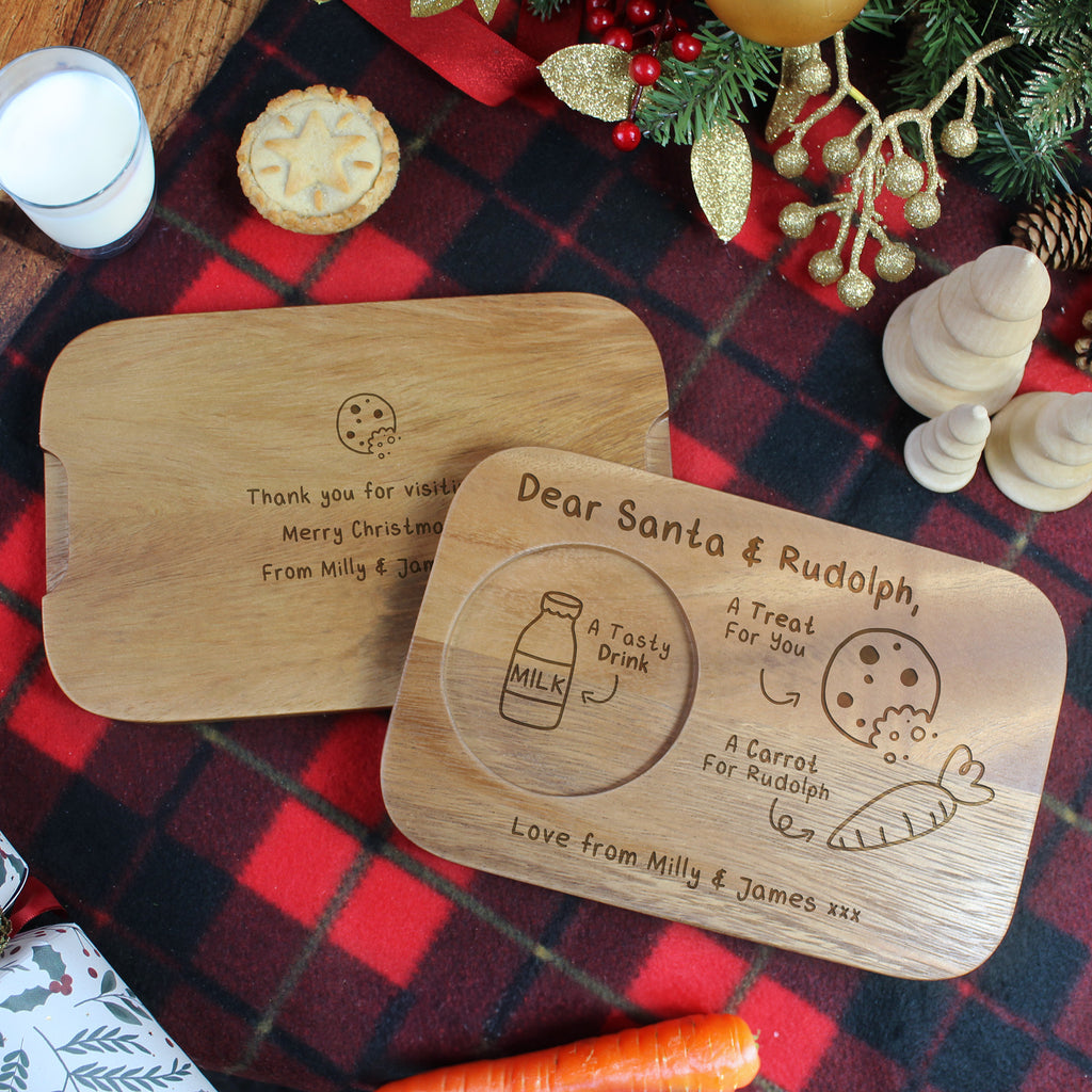 Two wooden Christmas plates with engraved messages on a plaid tablecloth.