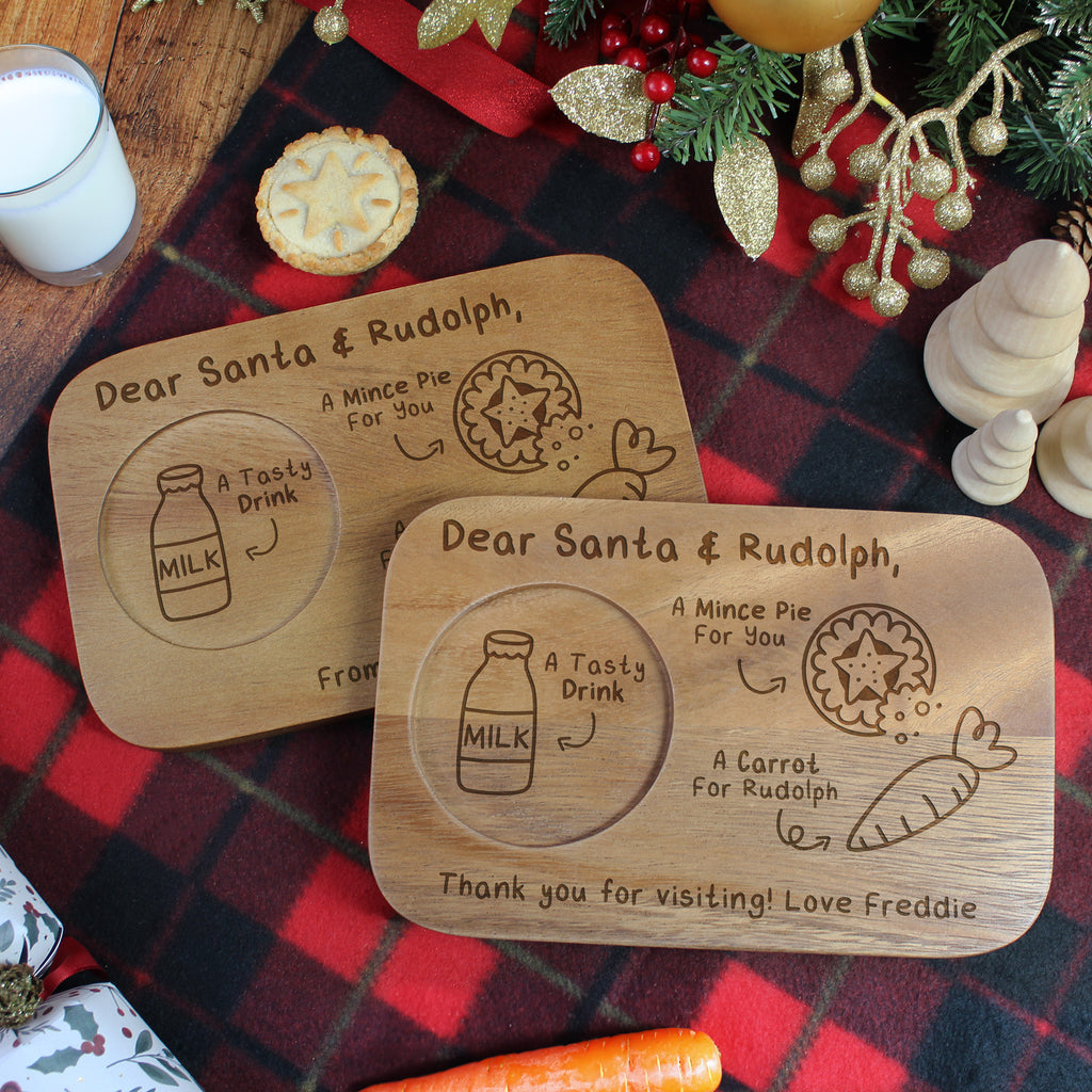Two wooden coasters with engraved Christmas messages on a festive tablecloth.