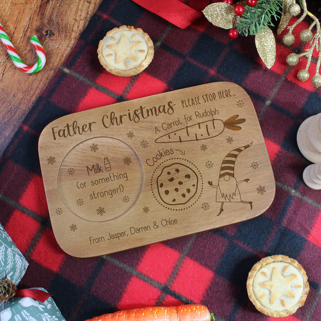 Wooden sign for Santa with cookies and milk, surrounded by Christmas decorations on a plaid fabric background.