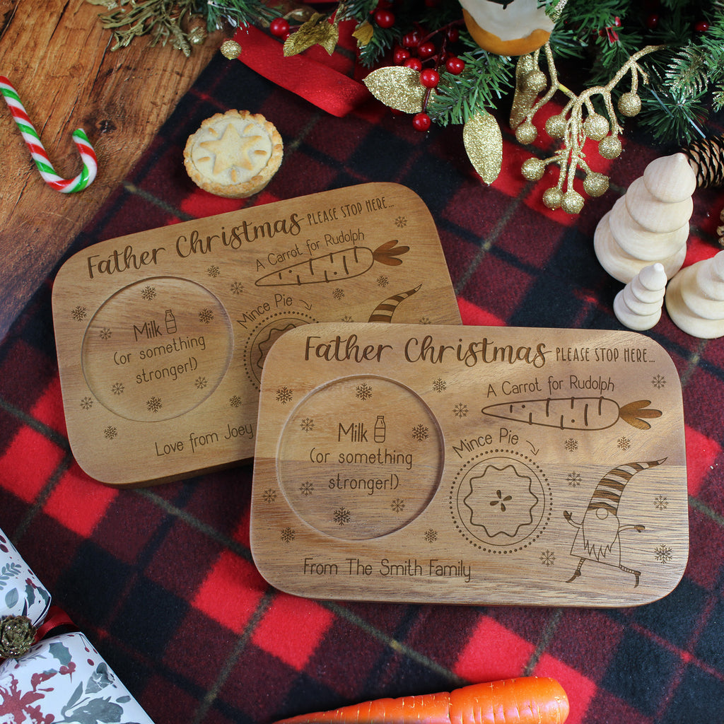 Two wooden Christmas Eve plates with engraved text on a festive background.