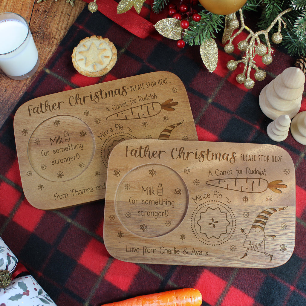 Two wooden Christmas Eve plates with engraved text on a festive tablecloth.