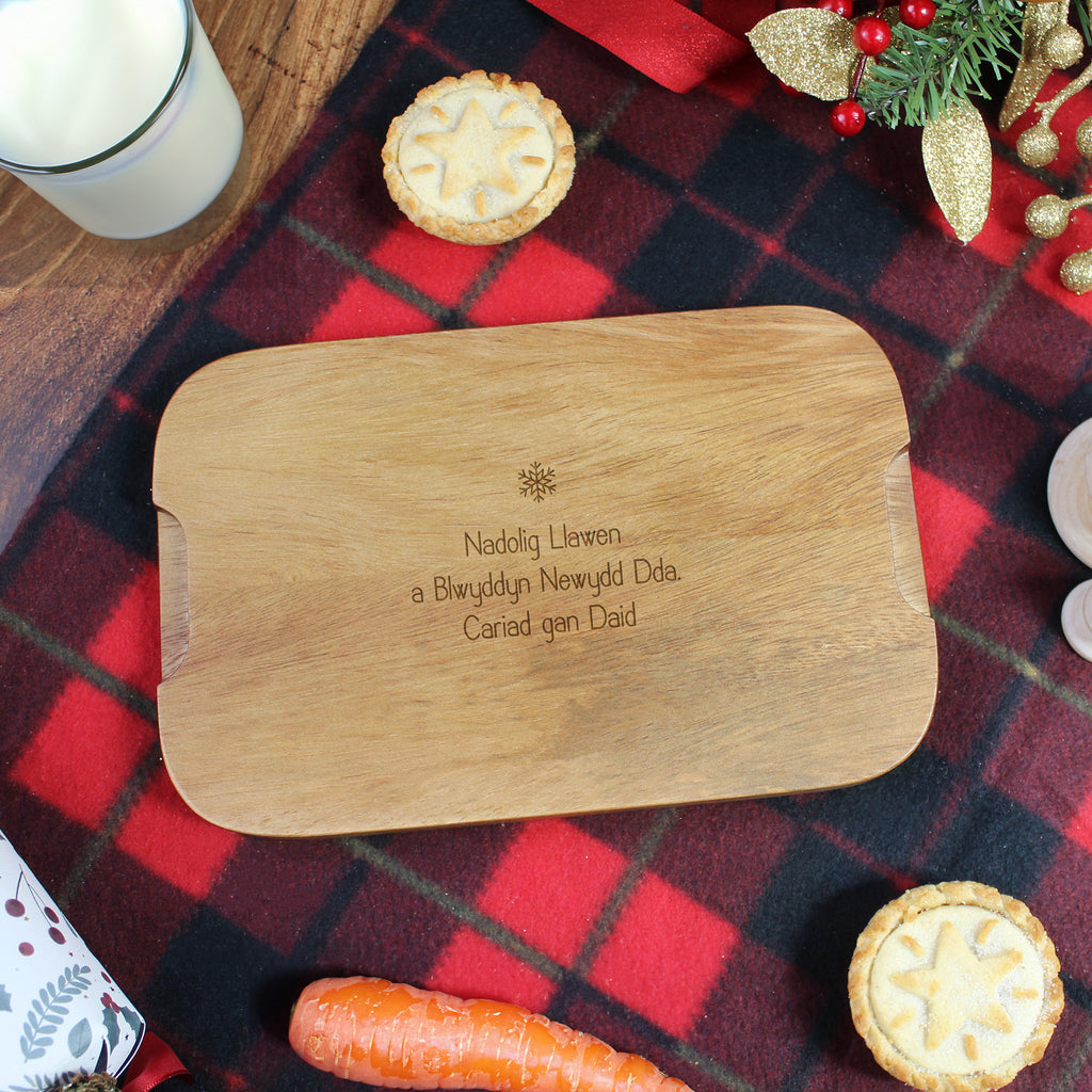 Wooden cutting board with engraved text on a red and black checkered tablecloth.