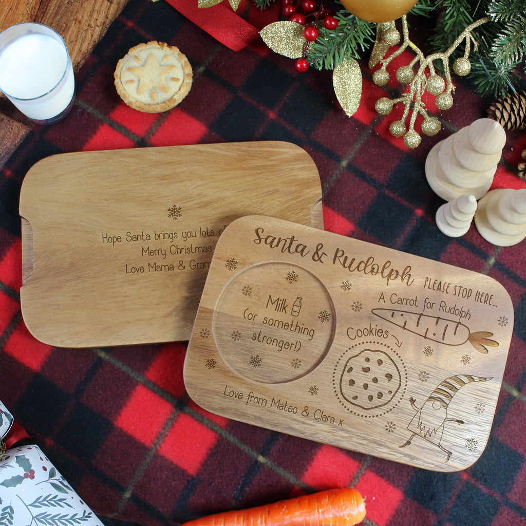 Two wooden Christmas-themed trays on a red plaid tablecloth with festive decorations.