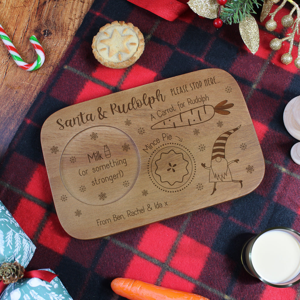 Wooden tray with engraved Christmas-themed design on a festive tablecloth.