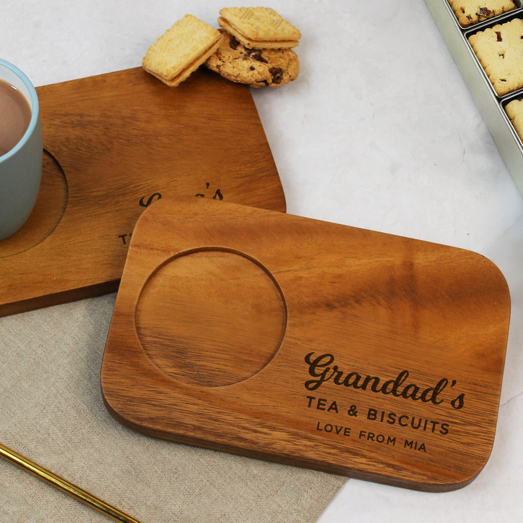 Wooden coasters with 'Grandad's Tea & Biscuits' engraving on a table with a mug, cookies, and spoon.