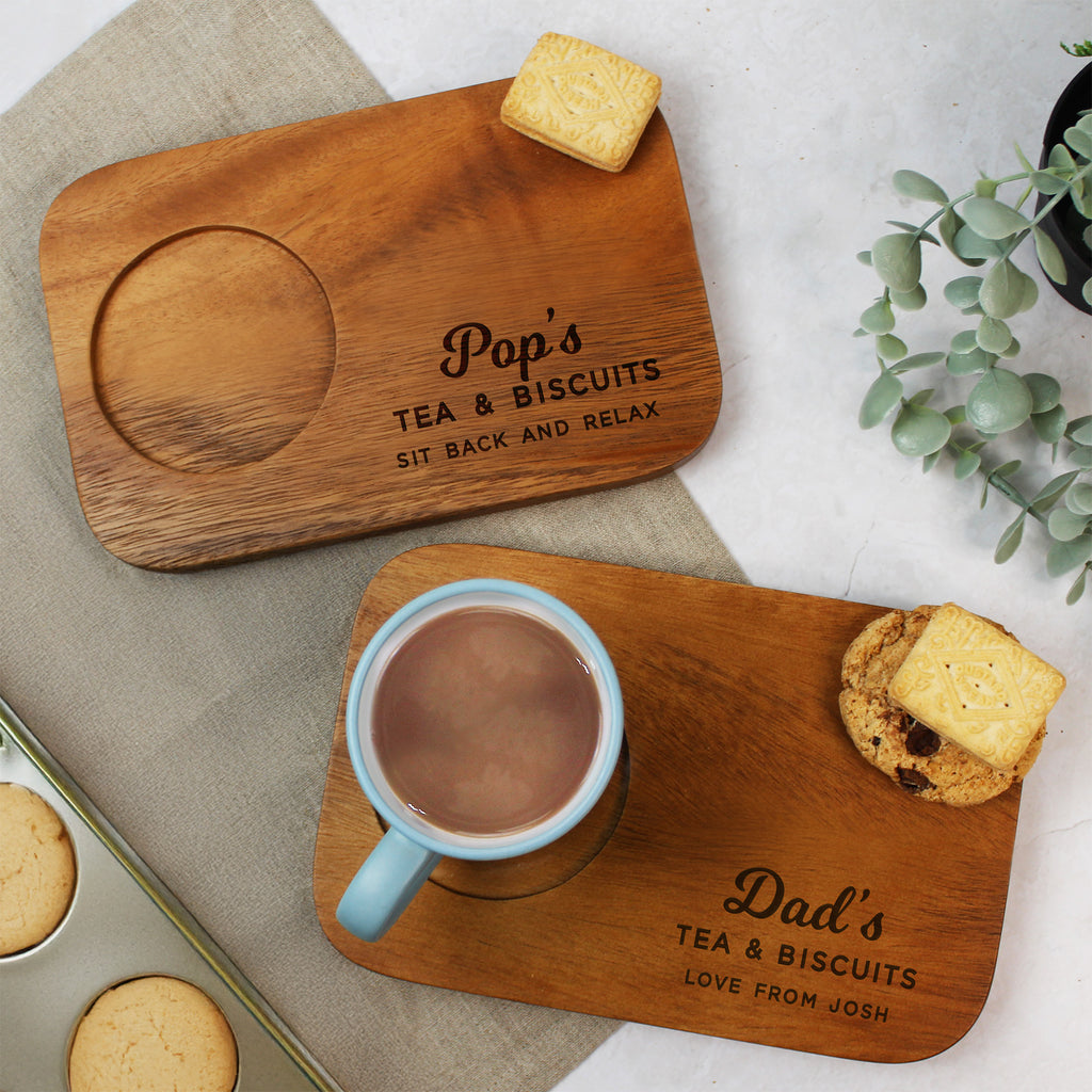 Two wooden trays with personalized inscriptions, one with a mug of tea and cookies, on a light background.