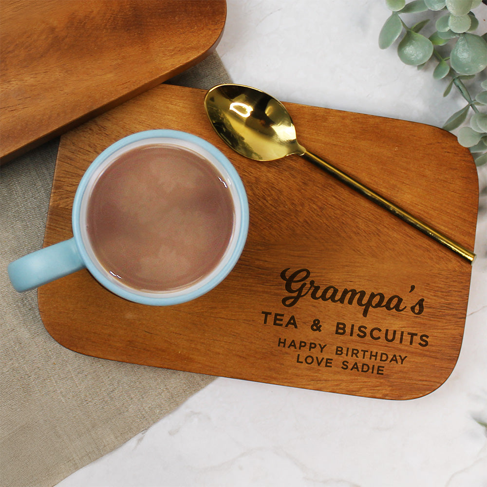Wooden tray with 'Grampa's Tea & Biscuits' inscription, mug of hot chocolate, and gold spoon.