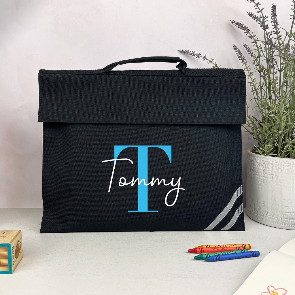 Black bag with 'Tommy' branding on a white surface with a plant in the background