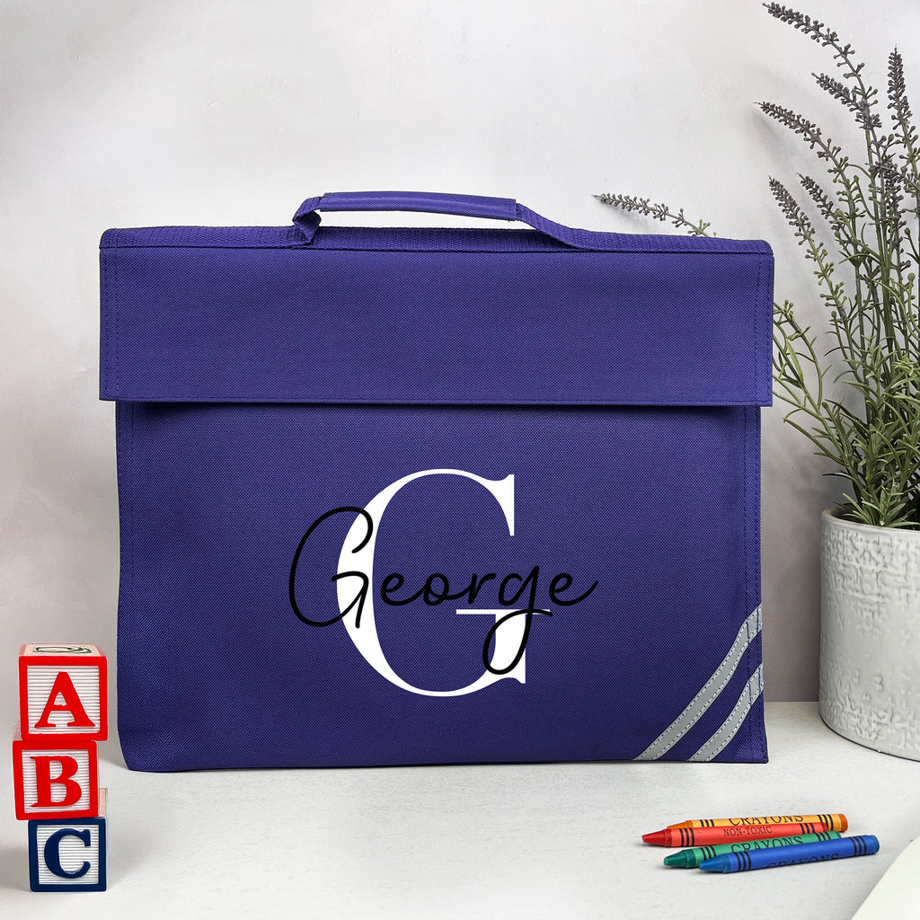 Blue bag with 'George' printed on it, placed on a white surface with educational items and a plant in the background.