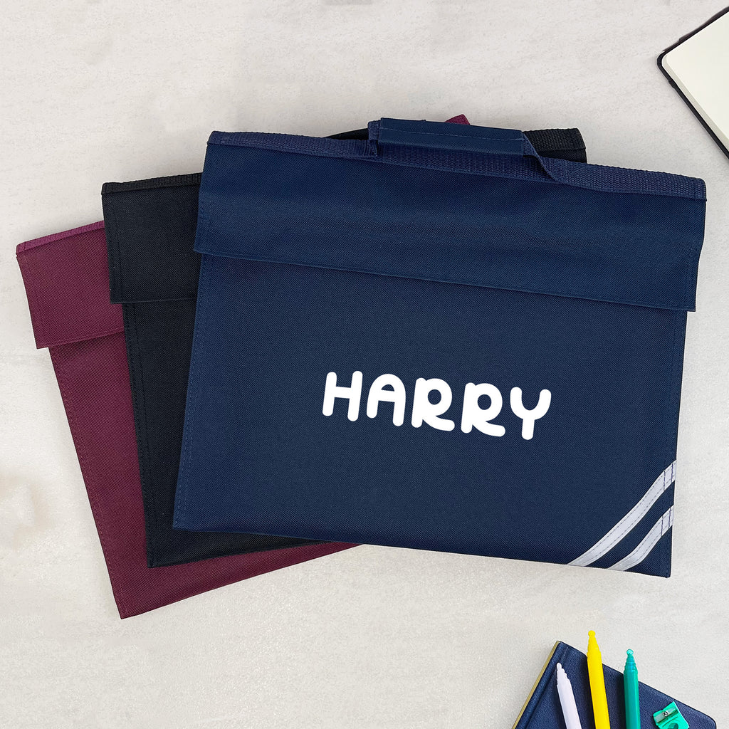 Navy bag with 'HARRY' printed on it, surrounded by stationery items on a light surface.
