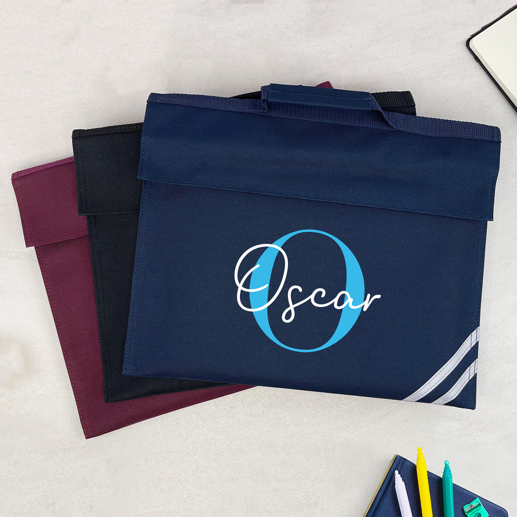 Navy bag with 'Oscar' monogram on a light surface with stationery items.