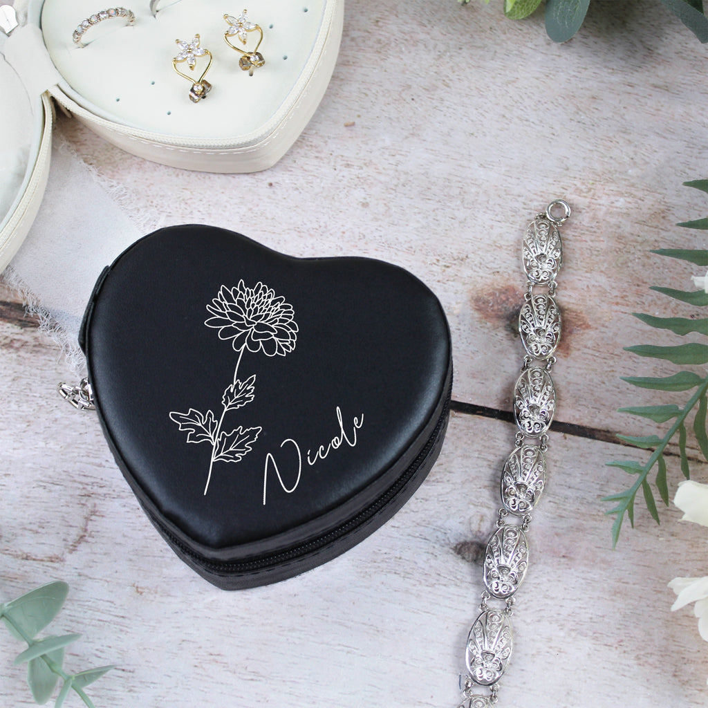 Black heart-shaped jewelry case with floral design and 'Nicole' text, next to a bracelet on a wooden surface.