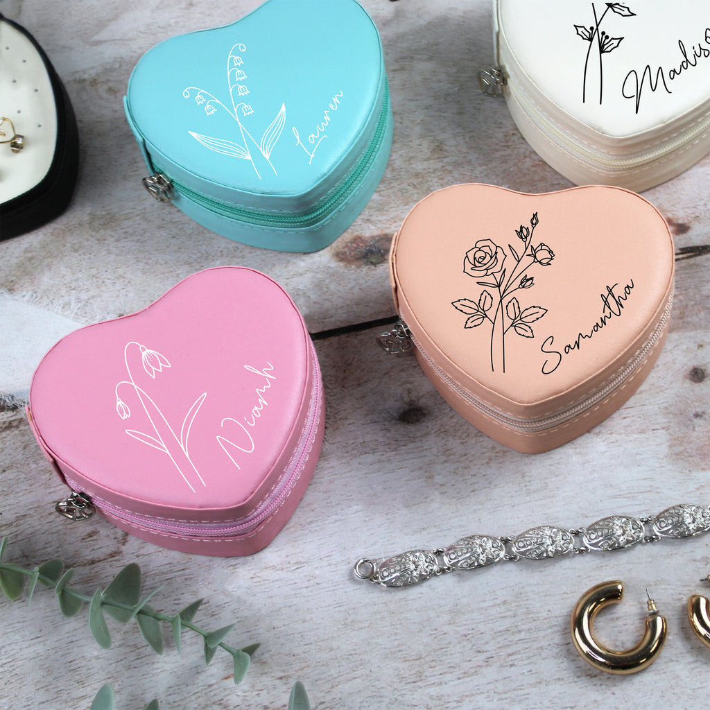 Heart-shaped jewelry cases with personalized names on a wooden surface with jewelry.