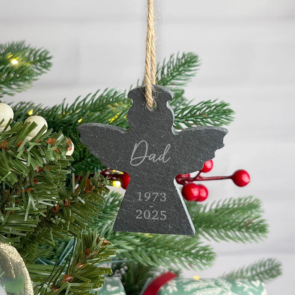 Decorative angel ornament with 'Dad' and years on a Christmas tree.