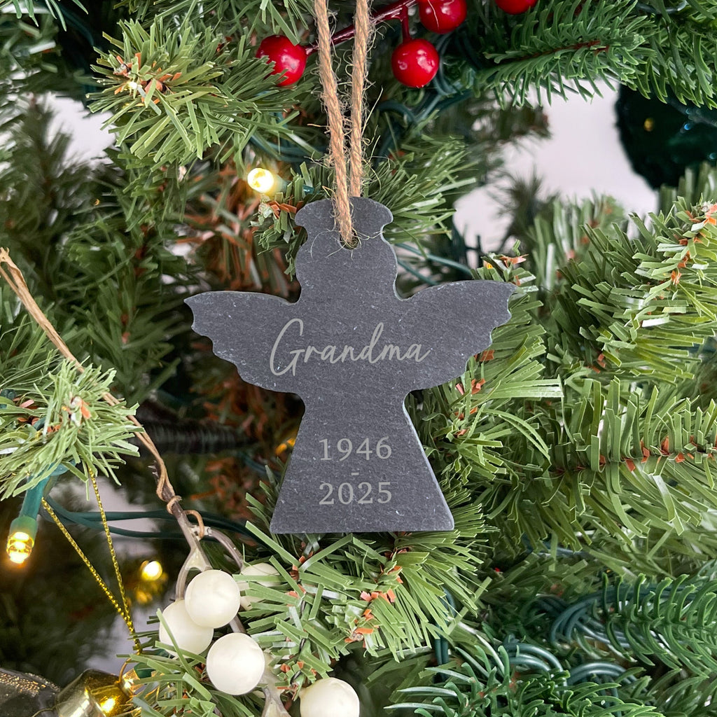 Decorative angel ornament with 'Grandma 1946-2025' on a Christmas tree.