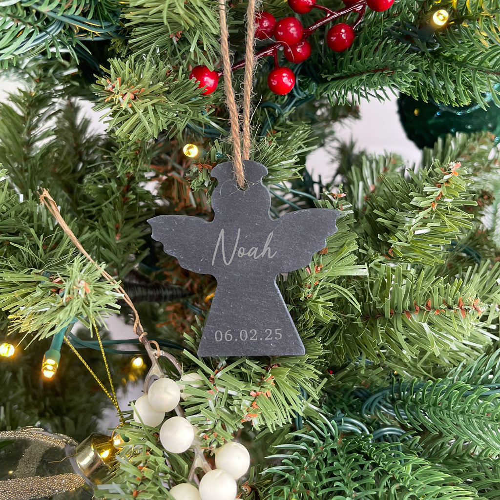 Decorative angel ornament with 'Noah' and date on a Christmas tree.