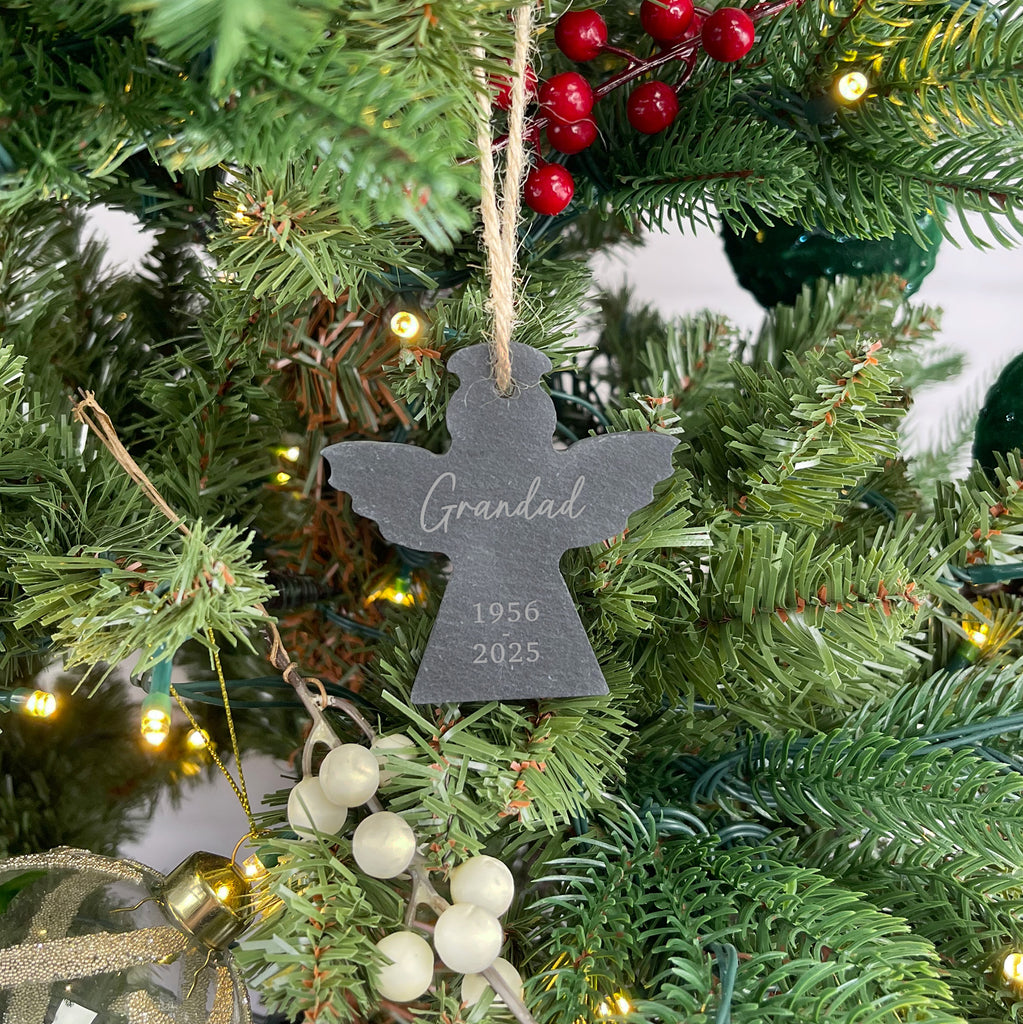 Decorative angel ornament with engraved text on a Christmas tree.