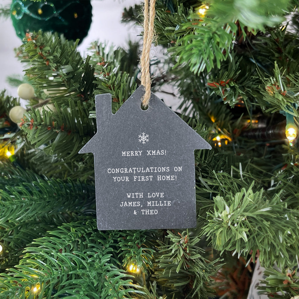 House-shaped Christmas ornament with personalized message on a decorated tree.