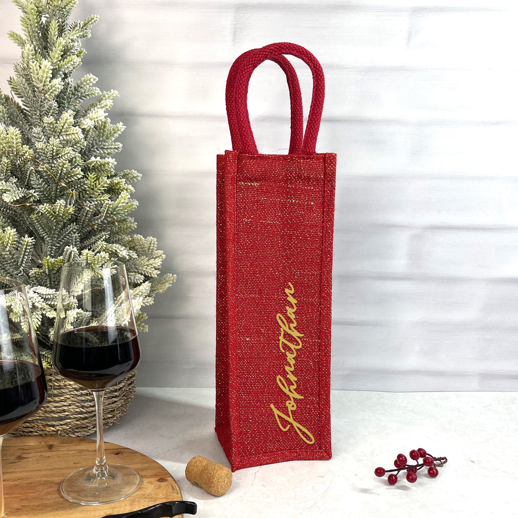 Red wine bottle bag with 'Johnathan' branding next to a glass of red wine and a Christmas tree.