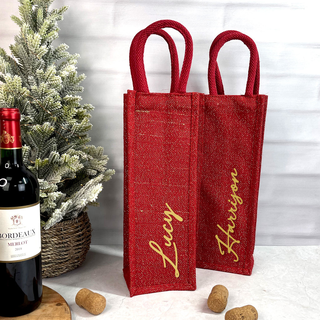 Two red wine bags with 'Lucy' and 'Harrison' names next to a bottle of Bordeaux wine.