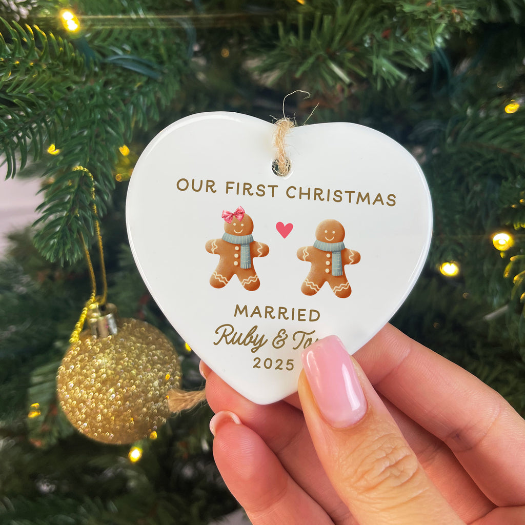 Heart-shaped ornament with 'Our First Christmas Married Ruby & Tom 2025' text and gingerbread men on a Christmas tree.