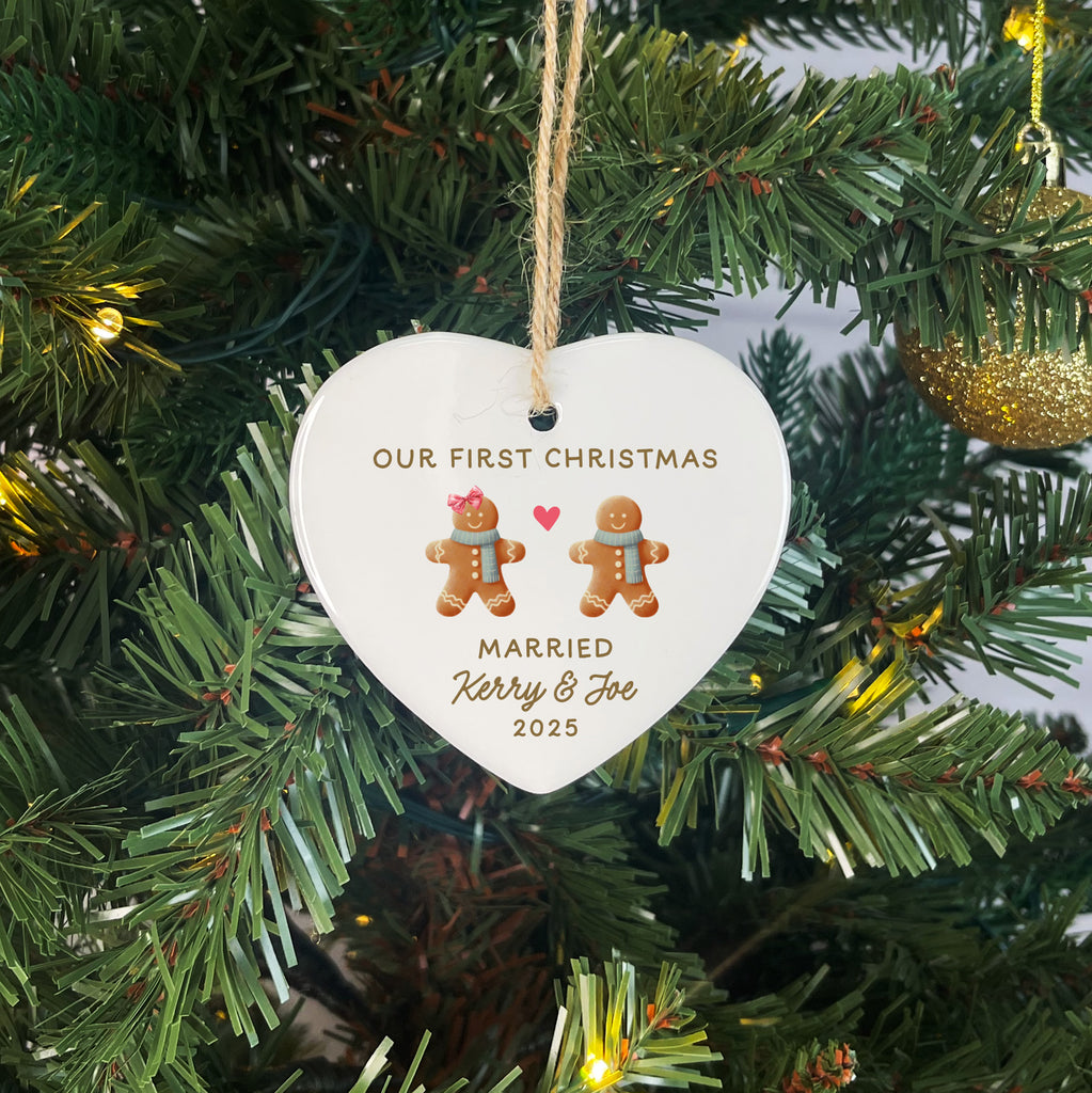 Heart-shaped ornament with gingerbread couple and text 'Our First Christmas Married Kerry & Joe 2023' on a Christmas tree.
