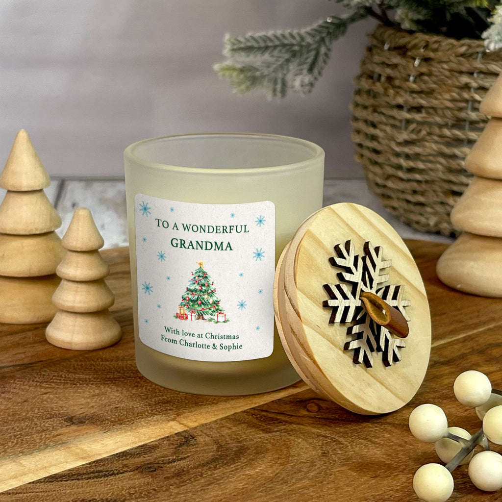 Festive candle with a decorative label on a wooden surface with Christmas decor.