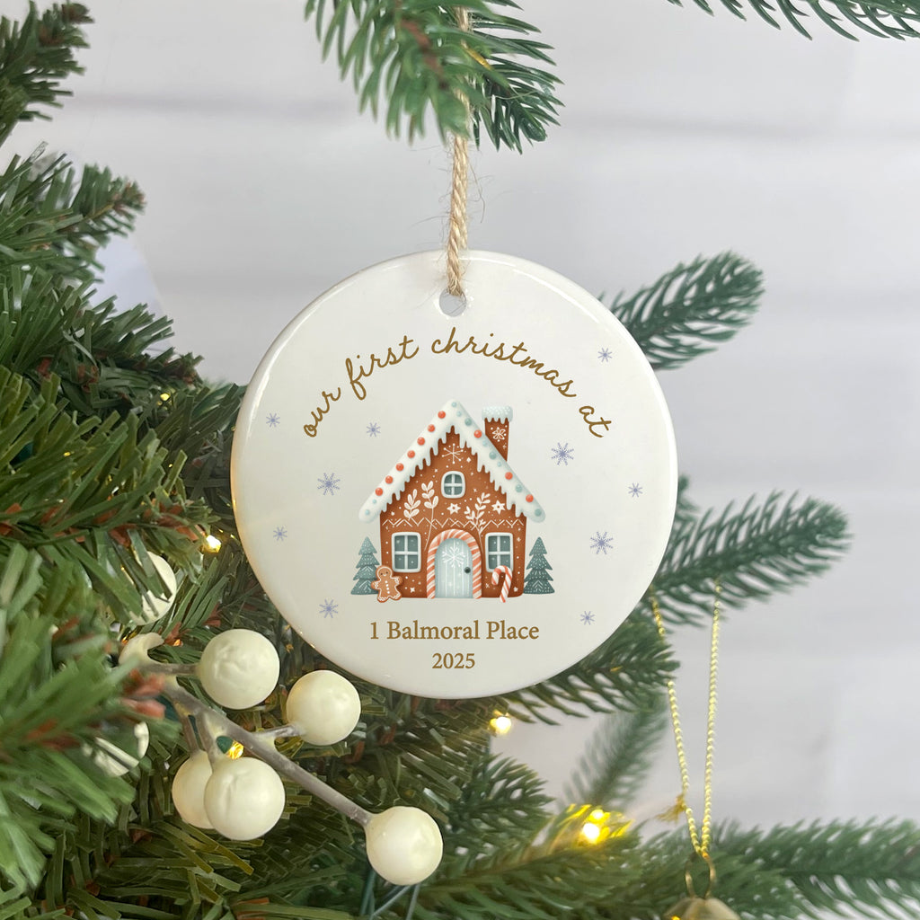 Christmas ornament with gingerbread house design and text on a tree.