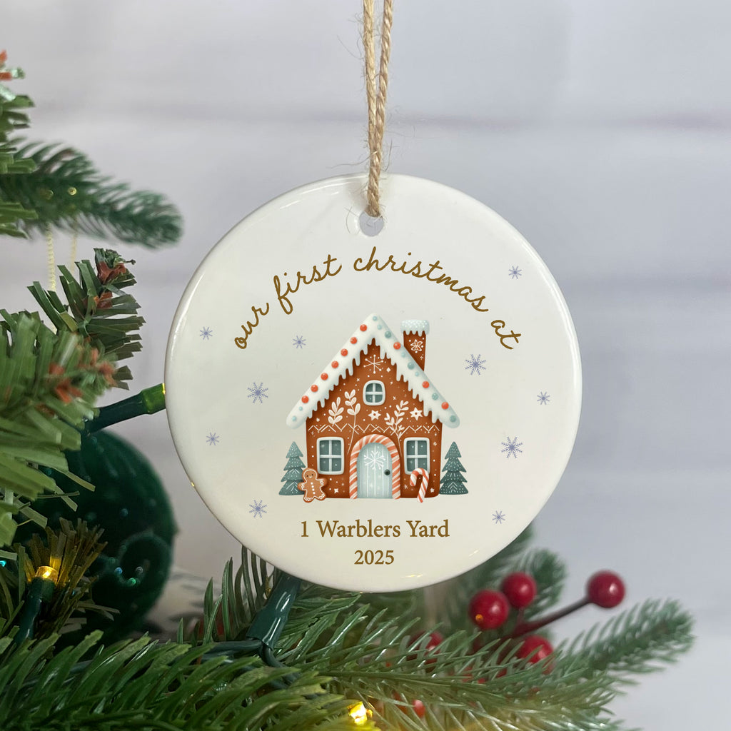 Decorative Christmas ornament with a gingerbread house design and text, hanging on a tree.