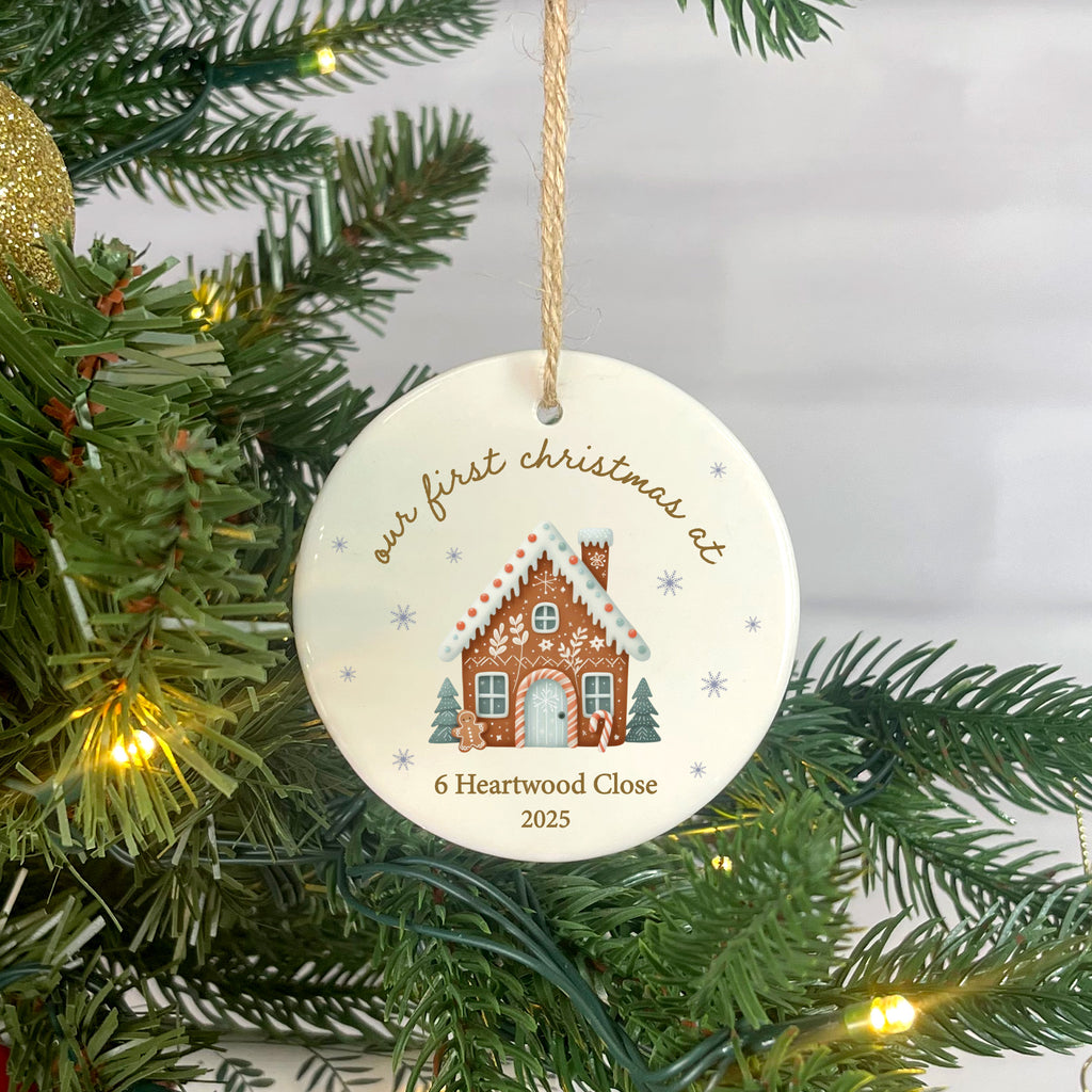 Christmas ornament with gingerbread house design hanging on a tree.