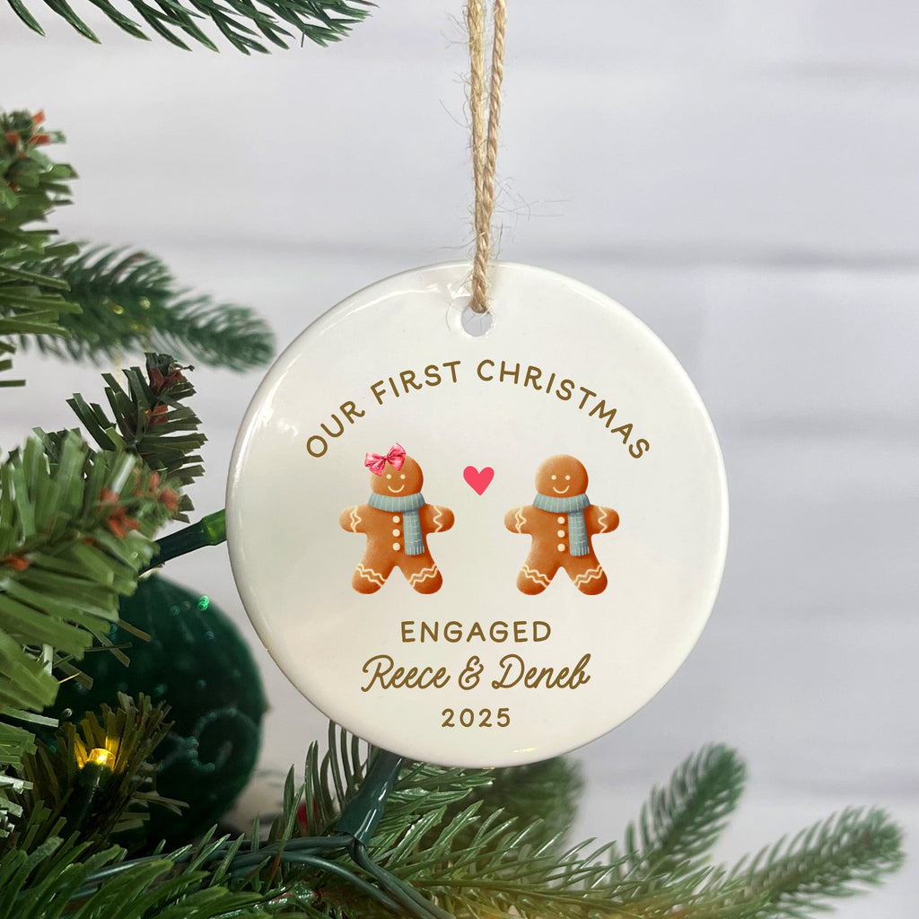 Personalized Christmas ornament with gingerbread couple and text, hanging on a tree.