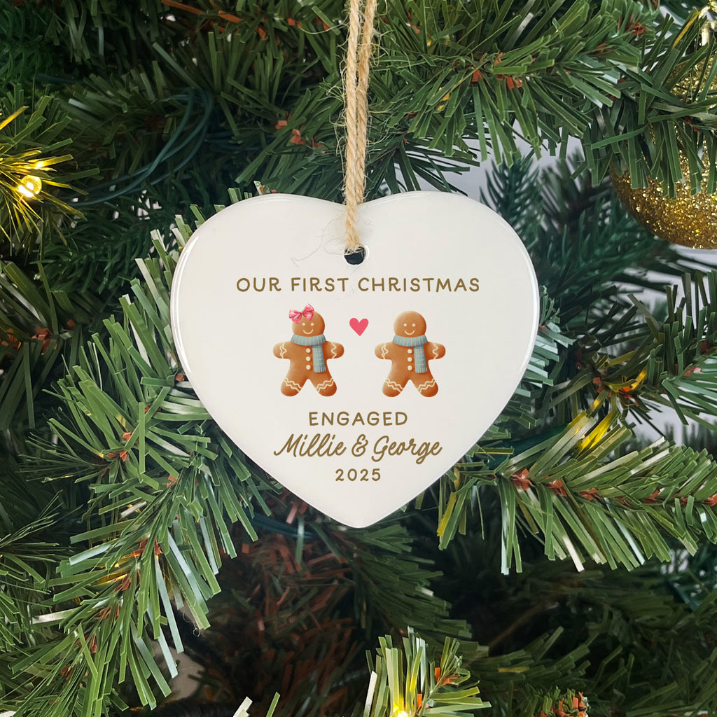 Heart-shaped ornament on a Christmas tree with 'Our First Christmas Engaged Millie & George 2025' text.