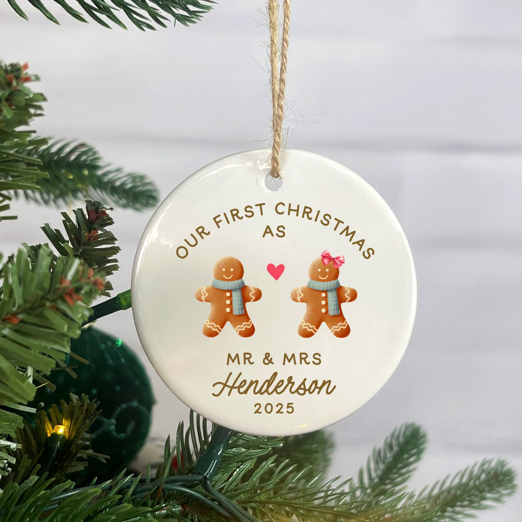 Personalized Christmas ornament with gingerbread couple and text 'Our First Christmas as Mr & Mrs Henderson 2023' on a tree.