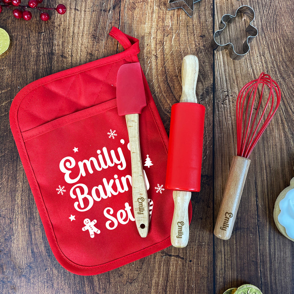 Red baking set with 'Emily Baking Set' apron, spatula, rolling pin, and whisk on a wooden surface.