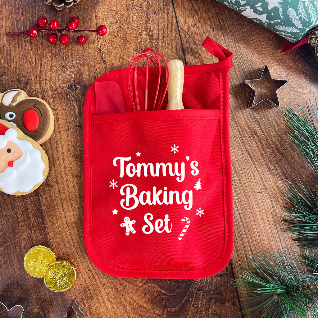 Red potholder with 'Tommy's Baking Set' on a wooden surface with baking-themed decorations.